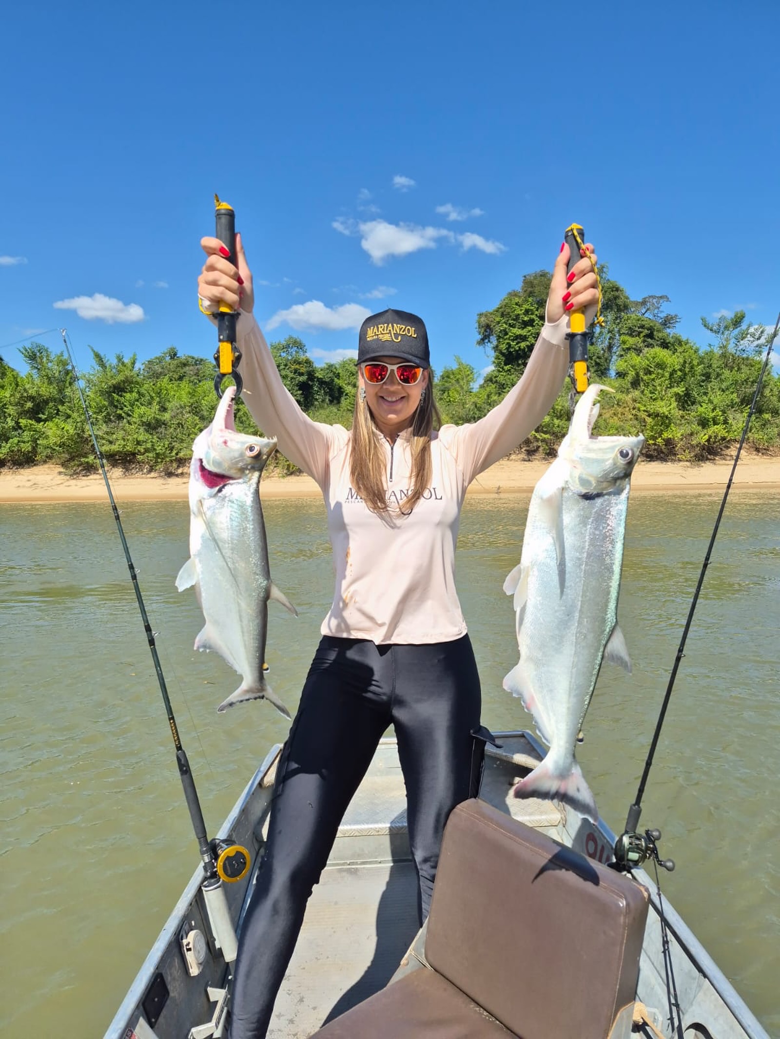 Pescadora exibindo dois peixes no barco
