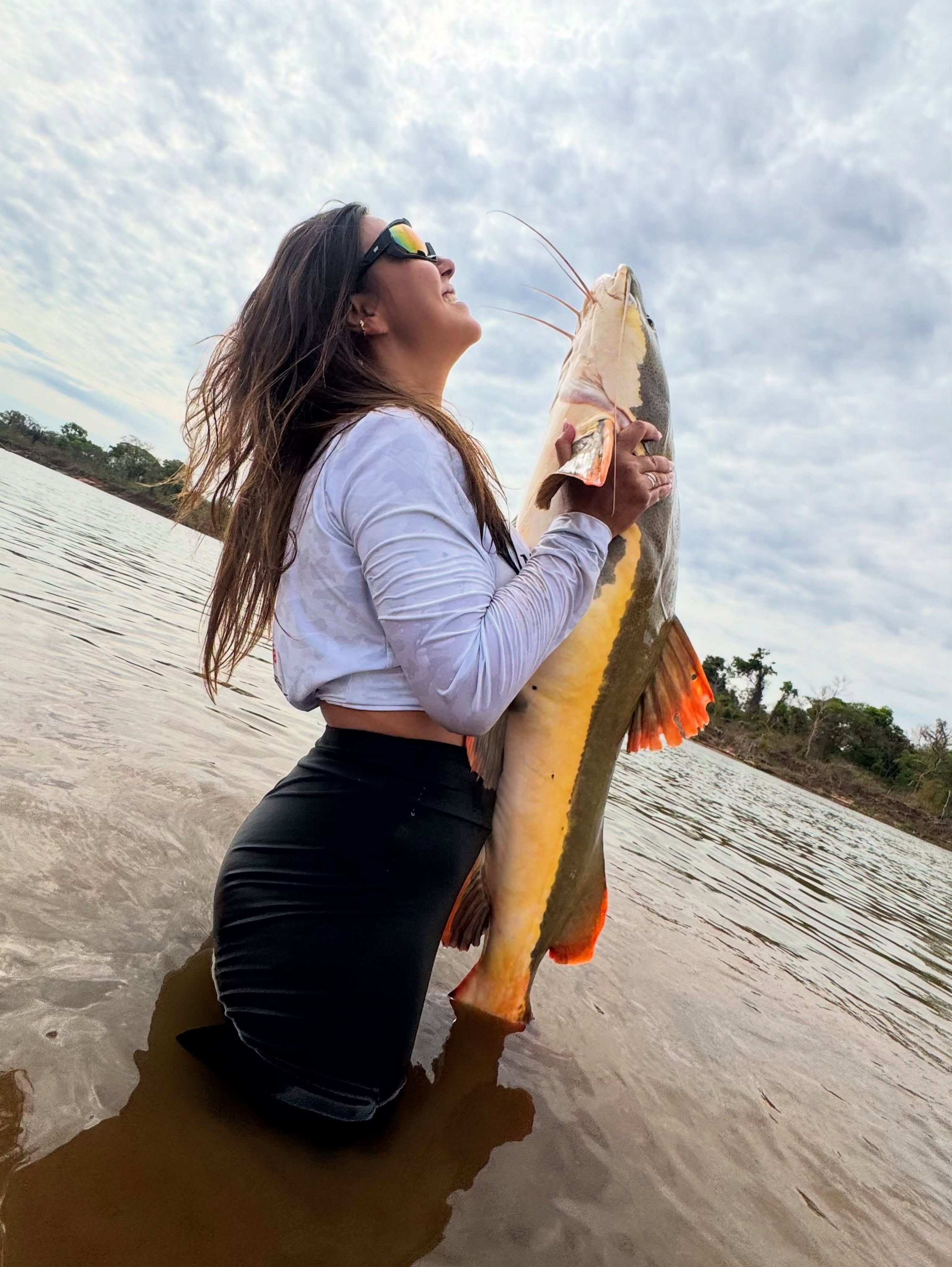 Pescadora no rio segurando um peixe recém-pescado