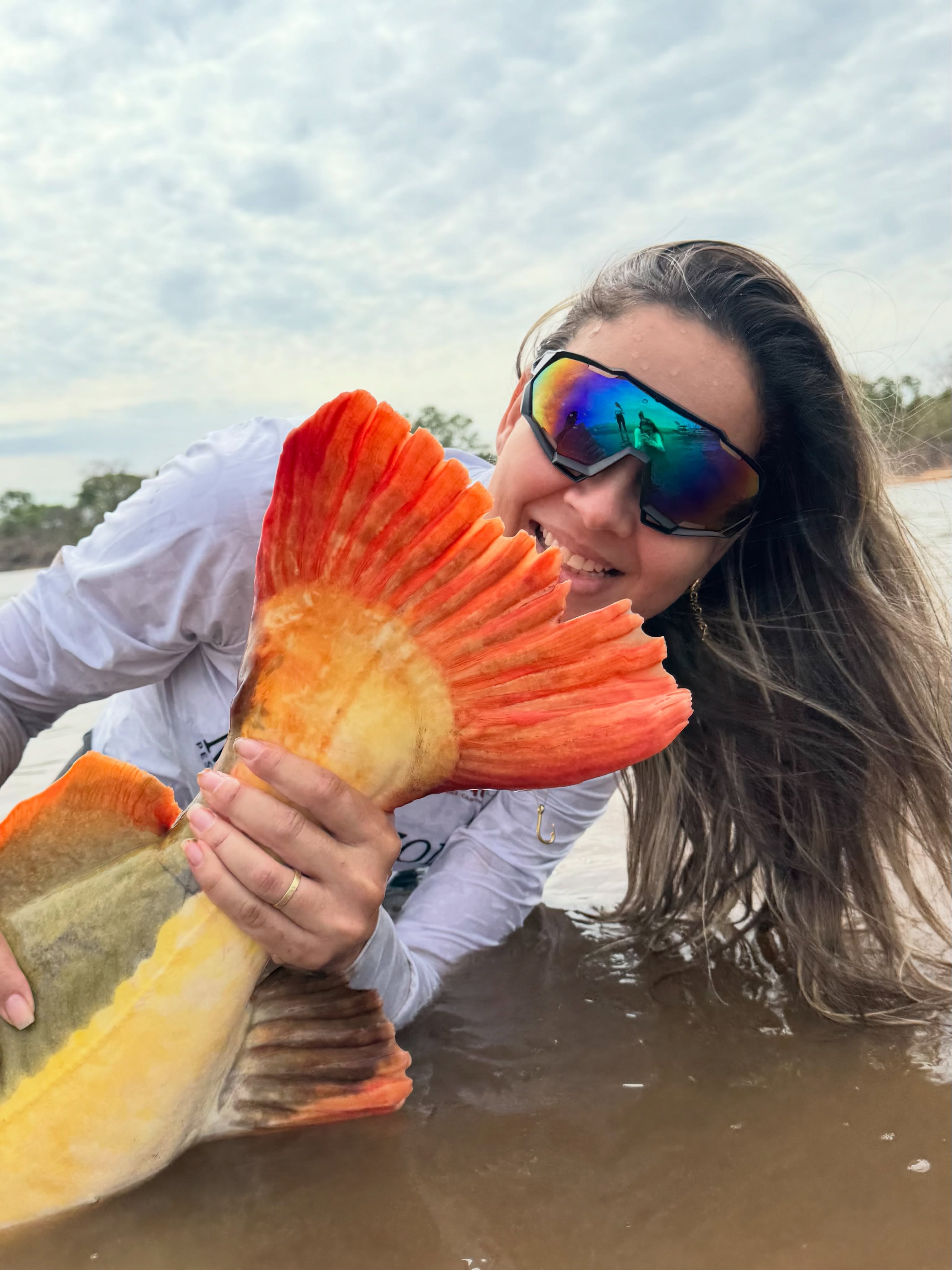 Pescadora sorrindo junto à cauda de um peixe